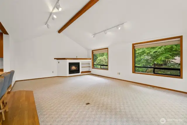 Vaulted great room with large windows and gas fireplace.