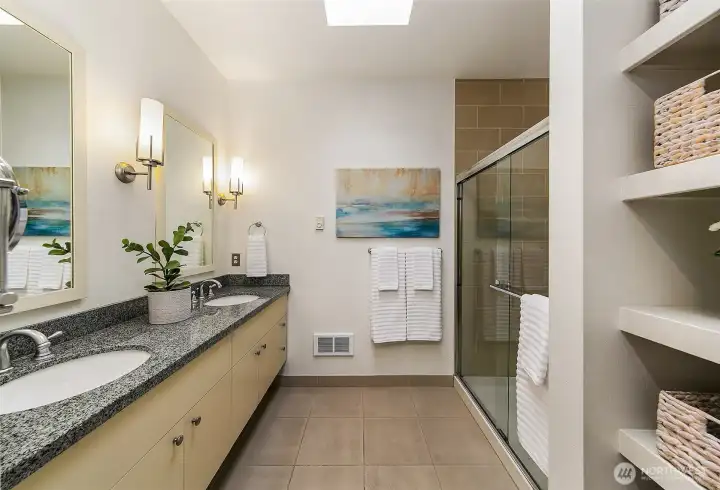 Primary bathroom features dual vanities and walk-in shower