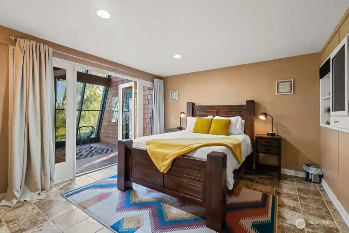 One of the lower level bedrooms with access to the atrium, hot tub and sprawling yards