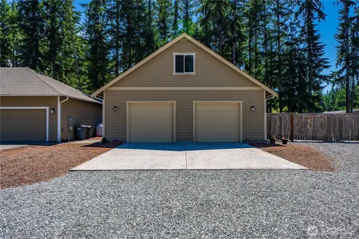 Detached two-bay shop with large concrete approach, upper storage area, and a convenient rear lawn mower bay with roll-up door. Detached two-bay shop with large concrete approach, upper storage area, and a convenient rear lawn mower bay with roll-up door.