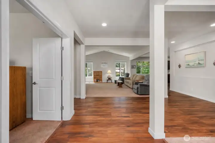 Wide interior view showcasing the open rambler layout, warm wood-style flooring, living room, dining area, and easy access to the primary suite. Wide interior view showcasing the open rambler layout, warm wood-style flooring, living room, dining area, and easy access to the primary suite.