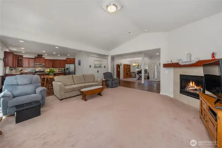 Open-concept living area with vaulted ceiling, cozy fireplace, kitchen and dining views, and spacious single-level flow throughout the home. Open-concept living area with vaulted ceiling, cozy fireplace, kitchen and dining views, and spacious single-level flow throughout the home.