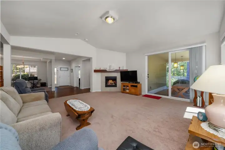 Spacious living room with vaulted ceiling, fireplace, large sliding glass door to the covered patio, and seamless connection to the entry and dining areas. Spacious living room with vaulted ceiling, fireplace, large sliding glass door to the covered patio, and seamless connection to the entry and dining areas.