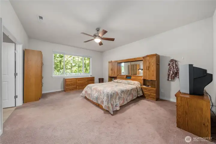 Spacious primary bedroom with ceiling fan, large window, soft carpet, and plenty of room for oversized furniture. Spacious primary bedroom with ceiling fan, large window, soft carpet, and plenty of room for oversized furniture.