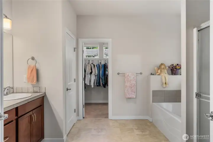 Primary bathroom featuring a soaking tub, separate shower, vanity area, tile flooring, and direct access to the walk-in closet. Primary bathroom featuring a soaking tub, separate shower, vanity area, tile flooring, and direct access to the walk-in closet.