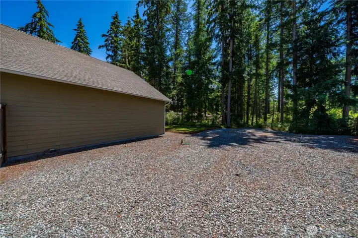 Gravel parking area beside the detached shop, offering additional space for trailers, equipment, recreational vehicles, or overflow parking. Gravel parking area beside the detached shop, offering additional space for trailers, equipment, recreational vehicles, or overflow parking.