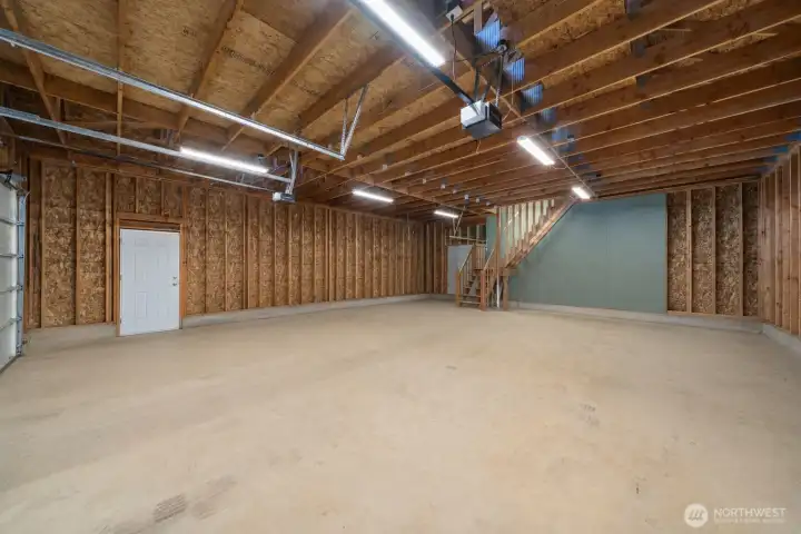 Expansive detached shop interior with high ceilings, concrete floor, garage doors, and impressive room for vehicles, tools, equipment, or projects. Expansive detached shop interior with high ceilings, concrete floor, garage doors, and impressive room for vehicles, tools, equipment, or projects.