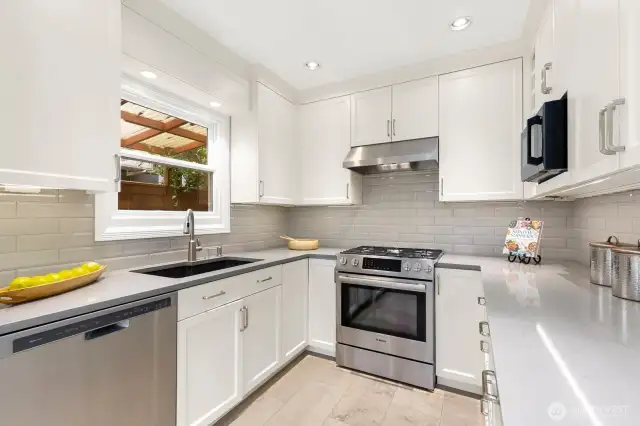 The remodeled epicurean kitchen features custom cabinetry, quartz countertops, stainless appliances, a cozy breakfast nook, and window seat.