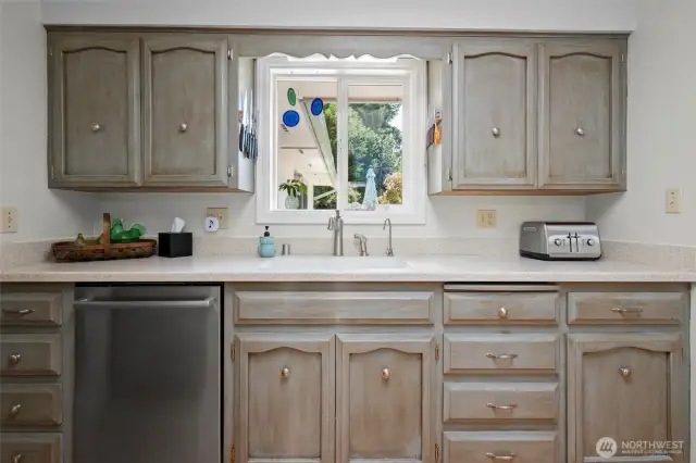 Plenty of storage in these beautifully custom painted cabinets. Window looks out to the back deck