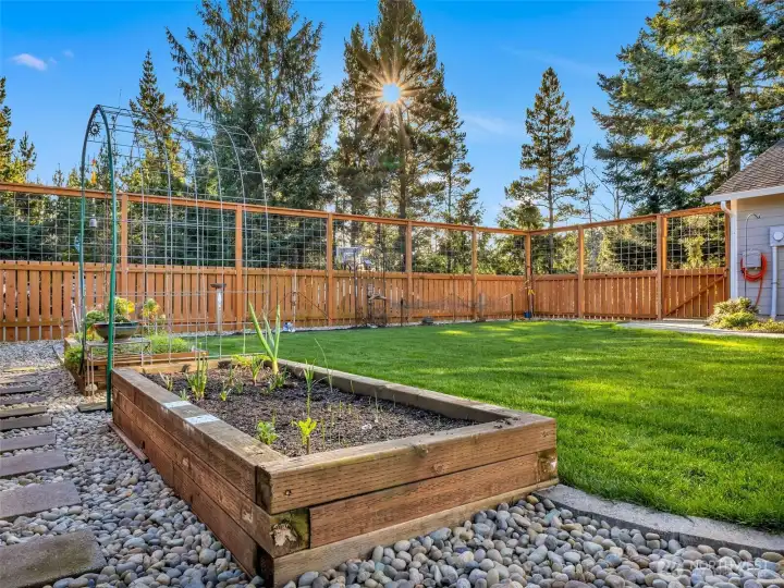 A new front yard features an 8’ deer-proof fence, sod lawn, paver patio, raised garden beds, and a welcoming sunroom entry—ideal for year-round enjoyment and gardening.