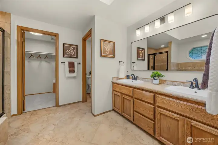 Primary 5 piece bathroom features handsome tile floors and counters, skylight and new lighting, mirror and paint.