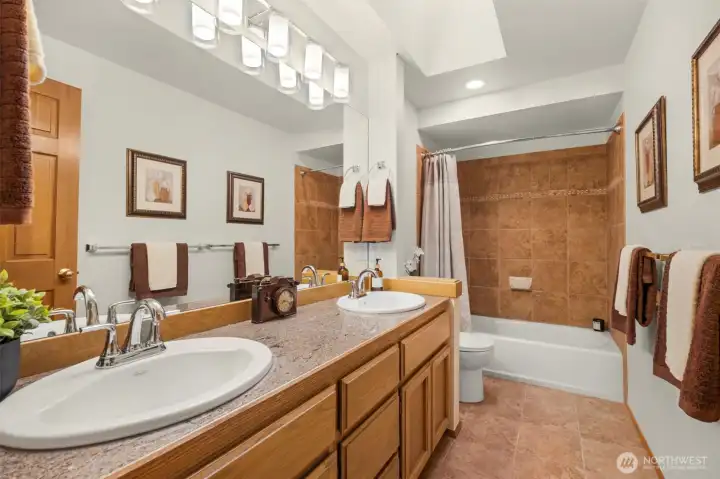 Main upstairs bathroom features beautiful tilework, skylight and new mirror and lighting.