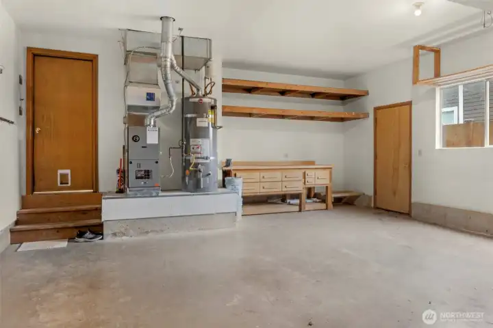 Garage interior with gas furnace and water heater plus work bench and built-in shelving