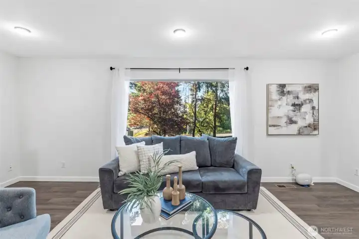 Large picture window overlooking the sloped front yard with mature landscaping everywhere you look.