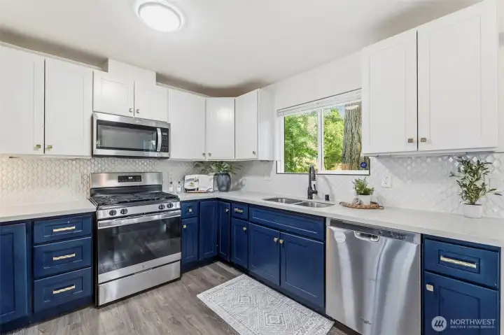 Updated kitchen with blue lower cabinets and white uppers. The hard surface countertops are aplenty in this kitchen.