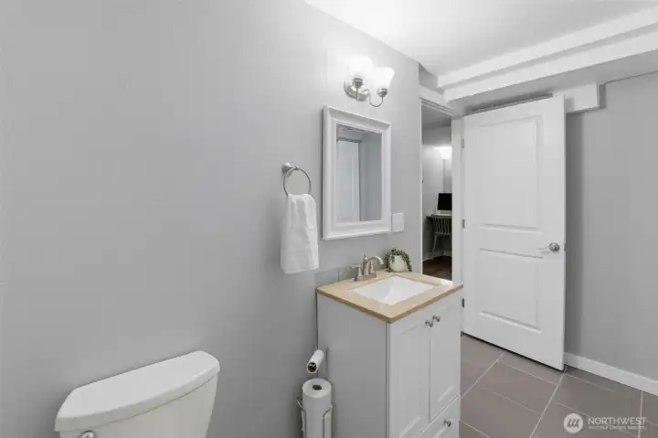 Lower level half-bath also houses the laundry area, concealed by sliding doors.