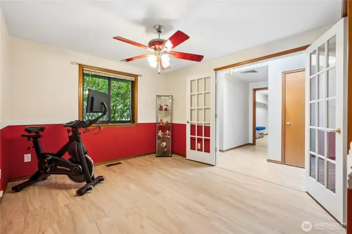 Fourth bedroom offering flexibility as a den, home office, or additional living space, with French doors opening to the entryway.