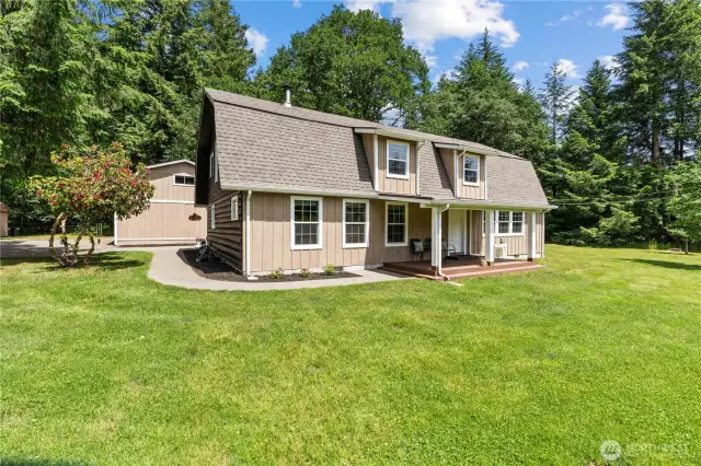 This inviting 2-story home sits peacefully in the center of a lush, open clearing surrounded by towering evergreens. With its classic cabin-style design, covered front porch & charming dormer windows, this home blends rustic appeal with modern updates. The expansive lawn is perfect for entertaining, outdoor dining, or simply relaxing in the quiet of nature. Enjoy morning coffee or evening BBQs in your private Pacific Northwest paradise—just under 10 acres of pure tranquility.