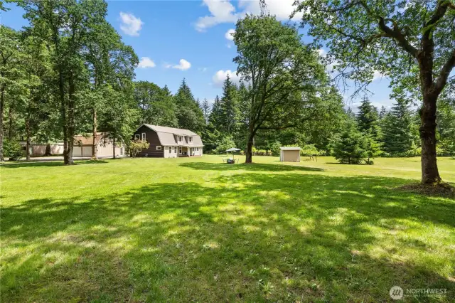 This expansive backyard view showcases the true beauty of living on nearly 10 acres of private, park-like land in Washington State. Surrounded by mature trees, open lawn, and peaceful forest views, the space offers endless potential for outdoor entertaining, gardening, or homesteading. The tranquil setting includes a cozy fire pit area, storage shed, and plenty of room for future expansion. Whether you're dreaming of a rural lifestyle retreat or a move-in ready acreage home, this property delivers space, serenity, and unmatched Pacific Northwest charm.