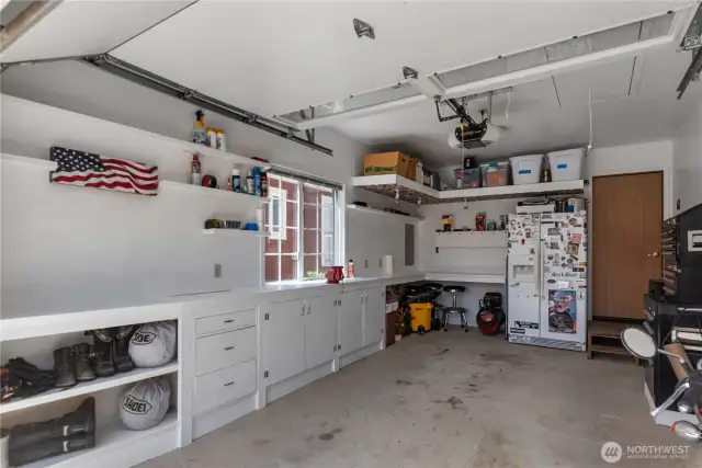 1 Car Garage with built in cabinets. The additional 2 car garage is attached to the house.  Attic storage with drop down ladder and wired lighting above.  Even a sign to remind you to turn the light off before you close it back up.  Vice on workbench stays with the house.