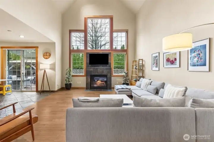 This is the room that makes an impression the second you step in. The vaulted ceiling pulls your eye up, then those five windows stacked across the wall take over, bringing in light all day and giving the fireplace a proper backdrop. The gas fireplace sits comfortably with its tile surround, simple and classic, while the wood wrapped windows and pane detailing add just enough character. Underfoot, the thick maple floors add a rich, grounded feel that balances all that openness. The palette stays warm and neutral, so it feels inviting right away, and with the slider nearby off the breakfast nook, it’s set up perfectly for easy indoor outdoor flow.