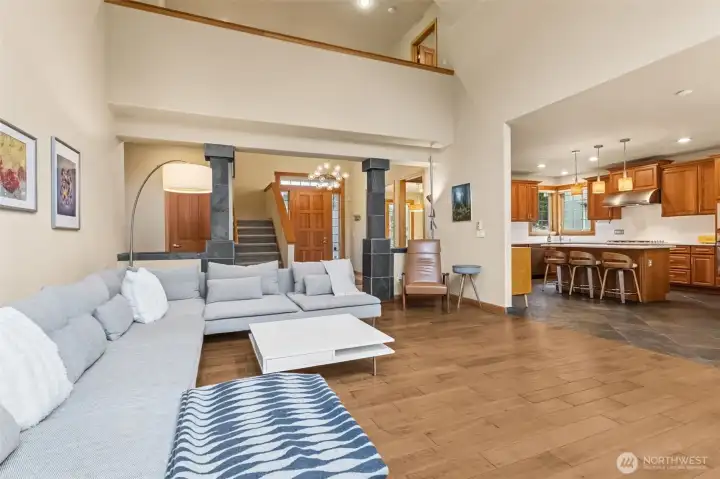 Standing here, you get the full picture of how this home lives day to day. The family room opens to the kitchen and breakfast nook, while the entry and staircase with lights, stay in view, along with that loft style hallway above that keeps the space feeling open. The island with seating anchors the kitchen side, making it easy to gather without crowding. What really stands out is the circular flow, you can move from the foyer through the main living area, into the kitchen and around to the dining or flex space, then right back to where you started. It keeps everything connected, but still gives each area its own purpose.