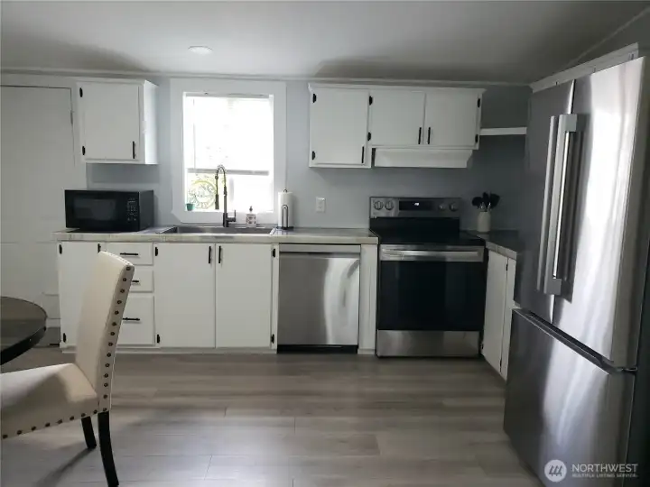 Another Picture of the Spacious Open Kitchen showing White Cabinets, New Stainless-Steel Appliances, White Painted Trim, Large Pantry, New Sink, Faucet, Counter Tops, LED Lighting, and Vinyl Plank Flooring. Another Picture of the Spacious Open Kitchen showing White Cabinets, New Stainless-Steel Appliances, White Painted Trim, Large Pantry, New Sink, Faucet, Counter Tops, LED Lighting, and Vinyl Plank Flooring.