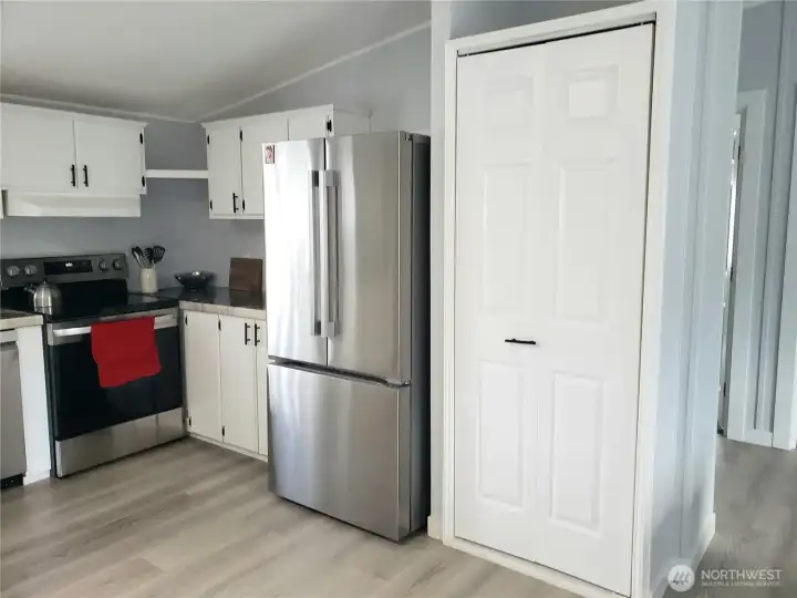 Another Different Picture of the Spacious Open Kitchen showing White 6 Panel Doors, Black Matte Hardware, Cabinets, New Stainless-Steel Appliances, White Painted Trim, Large Pantry, New Sink, Faucet, Counter Tops, LED Lighting, and Vinyl Plank Flooring.