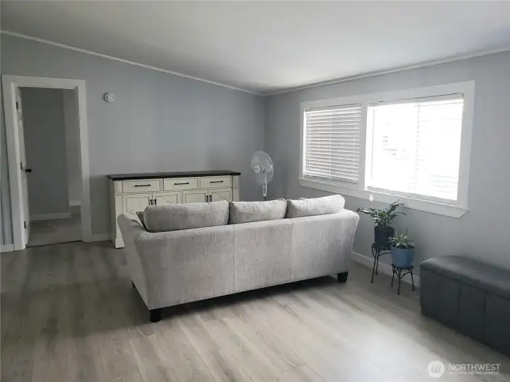 A Picture of the Huge Living Room Front the Primary Master Bedroom showing New Interior Paint, White Painted Trim and the New Vinyl Plank Flooring.