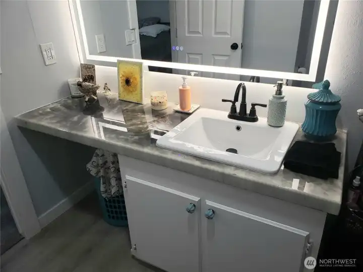 Another Picture of the Large Primary Master Bathroom showing New Sink, Faucet, Countertop, Lighted Vanity Mirror, Interior Paint, White Painted Trim and the New Vinyl Plank Flooring.