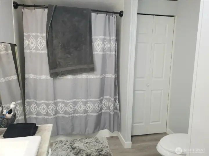 Another Picture of the Large Primary Master Bathroom showing New Sink, Faucet, Countertop, Lighted Vanity Mirror, Interior Paint, White Painted Trim, Linen Closet, Tub/Shower and New Vinyl Plank Flooring.