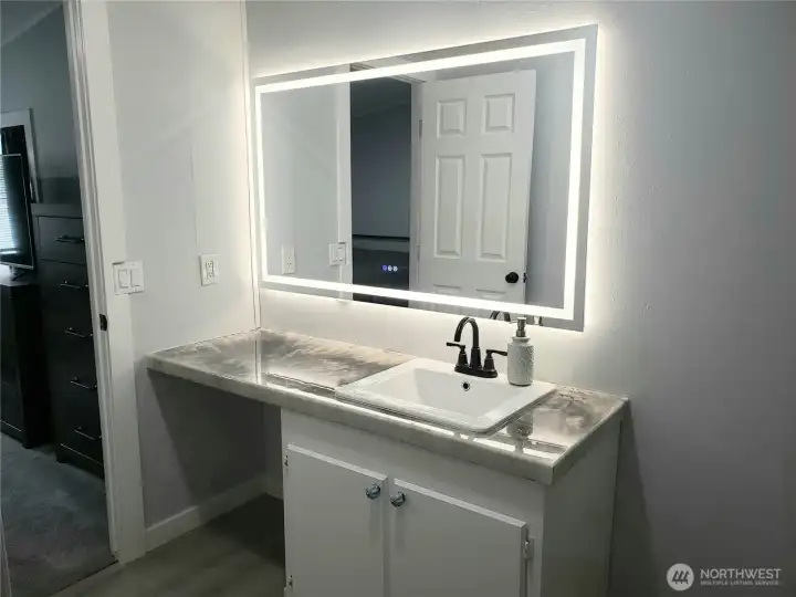 Picture of the Large Primary Master Bathroom showing New Sink, Faucet, Countertop, Lighted Vanity Mirror, Interior Paint, White Painted Trim and the New Vinyl Plank Flooring. Picture of the Large Primary Master Bathroom showing New Sink, Faucet, Countertop, Lighted Vanity Mirror, Interior Paint, White Painted Trim and the New Vinyl Plank Flooring.