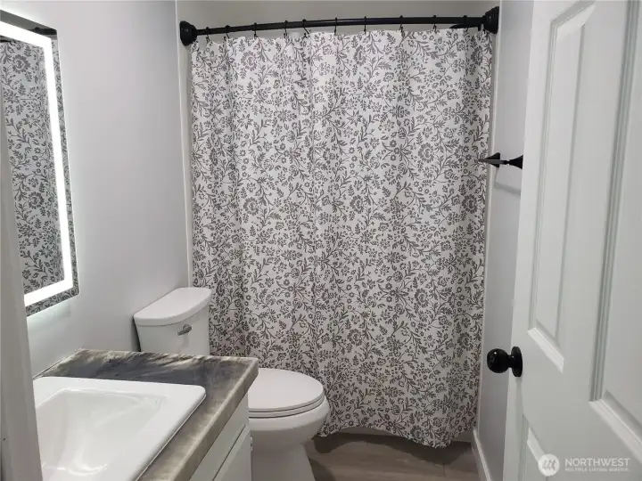 A Picture of the Large Main Guest Bathroom showing New Sink, Faucet, Countertop, Lighted Vanity Mirror, Tub/Shower, Interior Paint, White Painted Trim, New Vinyl Plank Flooring. A Picture of the Large Main Guest Bathroom showing New Sink, Faucet, Countertop, Lighted Vanity Mirror, Tub/Shower, Interior Paint, White Painted Trim, New Vinyl Plank Flooring.