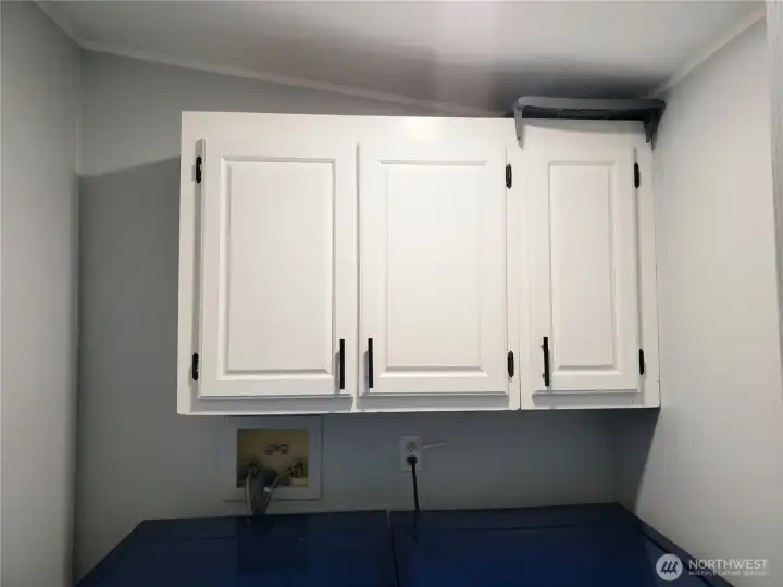 Another Picture of the Utility Room with 3 Storage Cabinets, Newer Vinyl Plank Flooring, Paint, Trim, and Washer and Dryer.