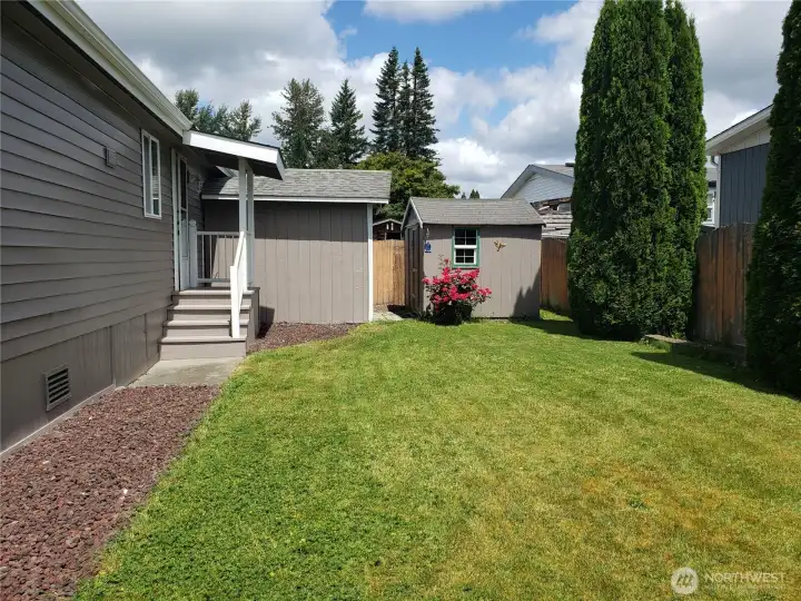 Another Opposite View of the A Picture of the Large Pet Friendly Fenced Backyard with Easy Care Landscaping Showing 2 Dry Storage Sheds and Covered Porch.