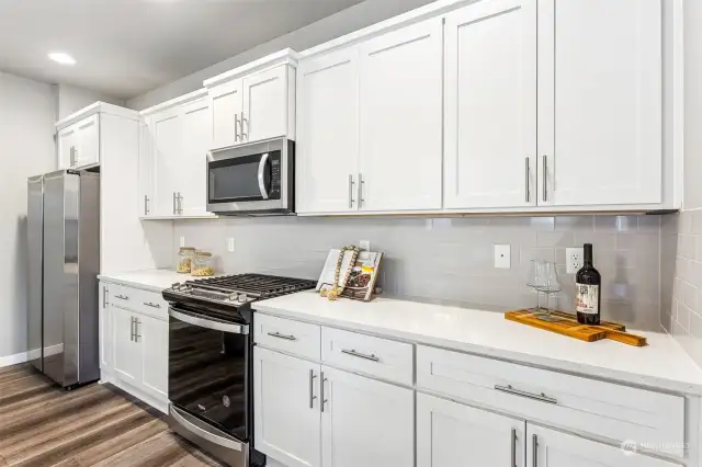 The kitchen is appointed w/white cabinets, a large island, quartz counters, SS appliances.