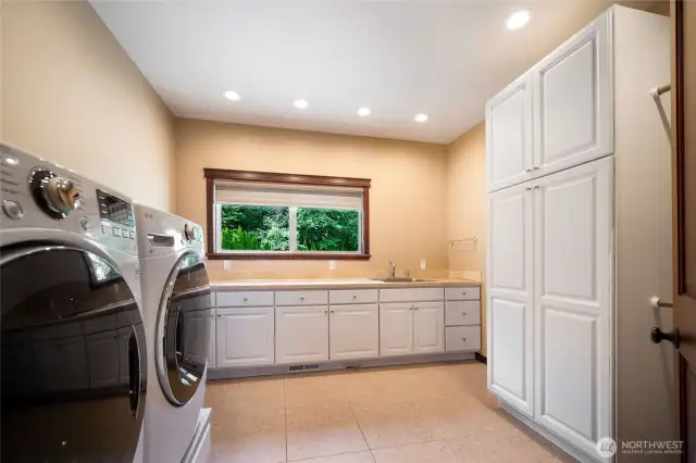 The utility room has plenty of storage, countertop space, and a utility sink.