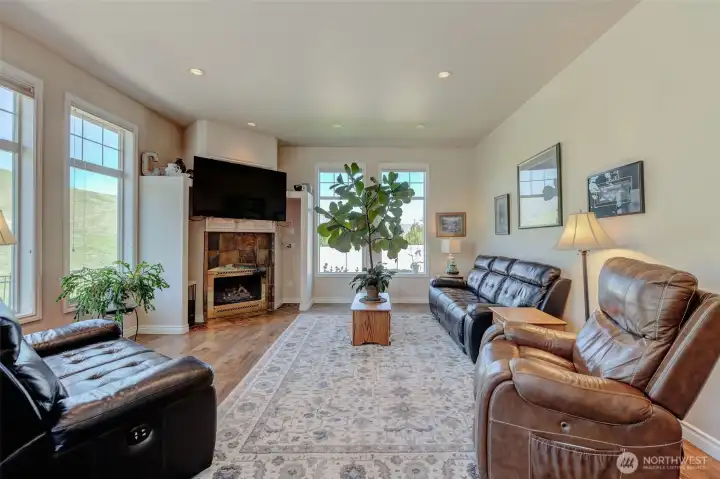 Open-concept living space highlighting updated hardwood flooring, large windows, and seamless connection to dining and kitchen areas.