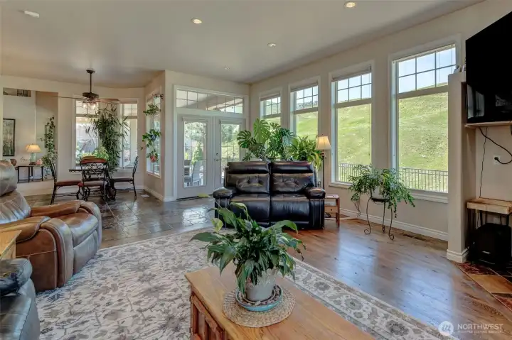 Open-concept living space highlighting updated hardwood flooring, large windows, and seamless connection to dining and kitchen areas.