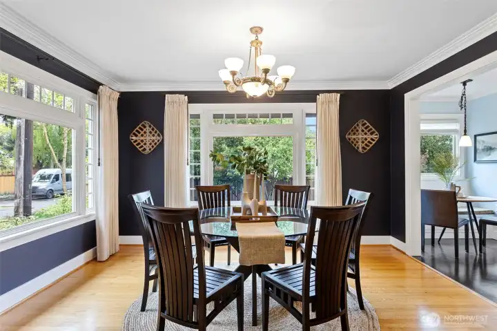 Deep navy walls, white crown molding, corner windows on two sides. The dining room doesn't whisper.