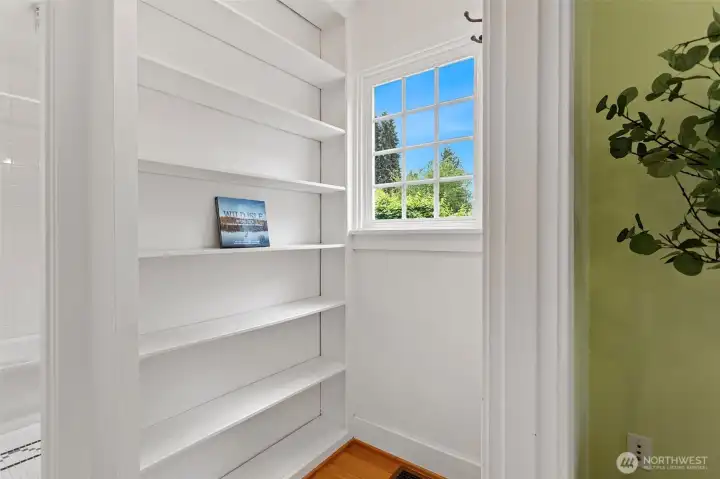 Built-in bookcase, stair landing, blue sky in the window. A pause before the Craftsman stops being modest.