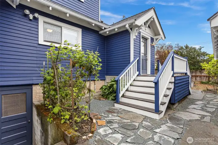 Off the kitchen, the split staircase drops you east to the garden or west toward the driveway and garage. New flagstone, exterior basement access just left of the stairs.