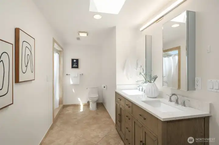 Sky-lit 3/4 en-suite bath in the primary suite features dual sinks.