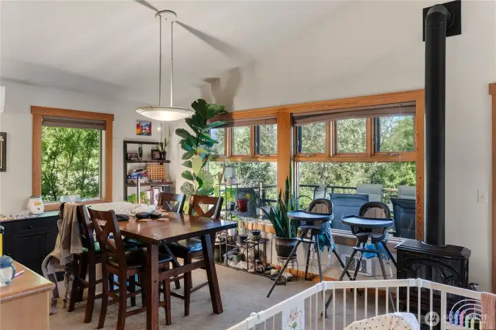 The dining area with a view into the trees at the edge of the yard through a stunning wood-framed window, and propane stove for a touch of coziness in the winter. The dining area with a view into the trees at the edge of the yard through a stunning wood-framed window, and propane stove for a touch of coziness in the winter.