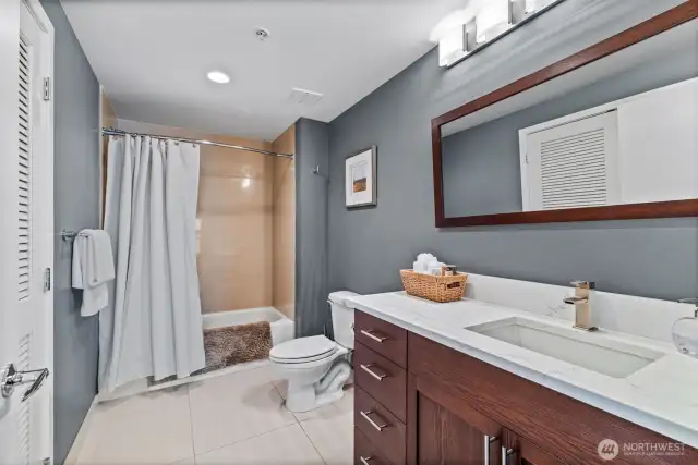The full-size bathroom is off th hallway, across from the seond bedroom. The slate countertop and irror are new upgrades. The louvered laundry room doors are shown on the left.