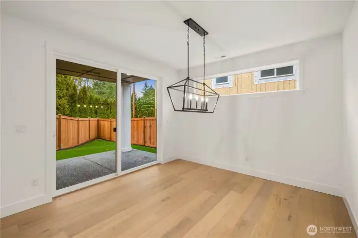 This dining area is filled with natural light from the wide sliding glass doors and high horizontal window, creating a warm and welcoming space. The modern chandelier anchors the room and opens to the covered patio for easy indoor-outdoor dining. It’s an ideal setup for everyday meals, hosting friends, or simply enjoying the private backyard setting.    These photos are from Lot 3 at Gooden Hollow, which is the same floorplan. However, Lot 6 will have changes, so all photos, renderings, site maps, and floorplans are for visualization purposes only. Plans, colors, building orientation, finishes, home outlook, and other details can and WILL vary.