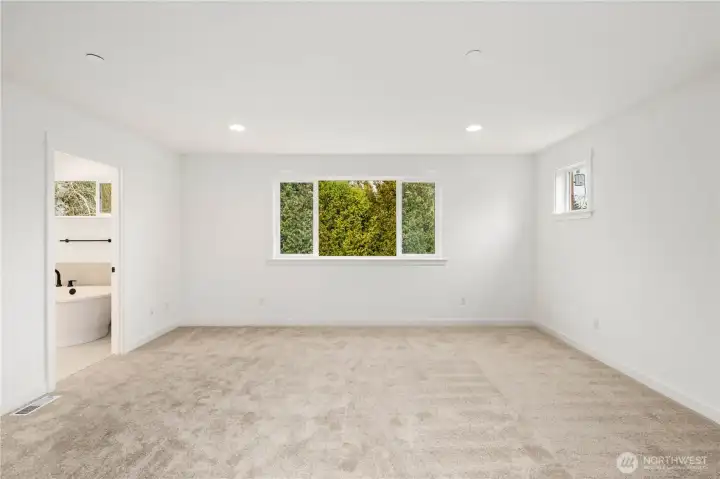 This spacious and light-filled suite offers a serene retreat with large windows overlooking lush greenery for added privacy and calm. Its generous layout easily accommodates a variety of furniture configurations, creating a restful space to unwind at the end of the day.    These photos are from Lot 3 at Gooden Hollow, which is the same floorplan. However, Lot 6 will have changes, so all photos, renderings, site maps, and floorplans are for visualization purposes only. Plans, colors, building orientation, finishes, home outlook, and other details can and WILL vary.