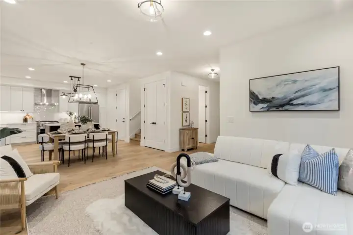 Open-concept living and dining area with recessed lighting, ceiling fixture, and light wood flooring.