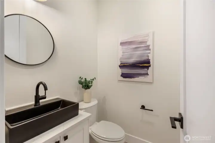 Bathroom with quartz countertop, recessed lighting, white walls, and black fixtures.