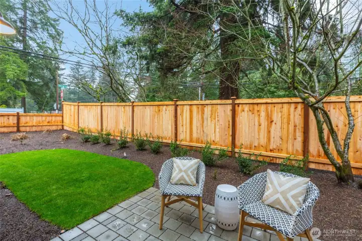 Patio complimented by a fenced in landscape.